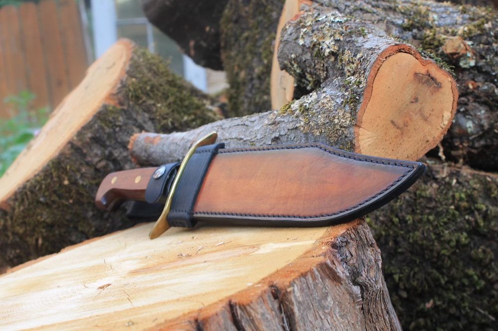 The same knife seated in its sheath, showing the welt and the burnished throat