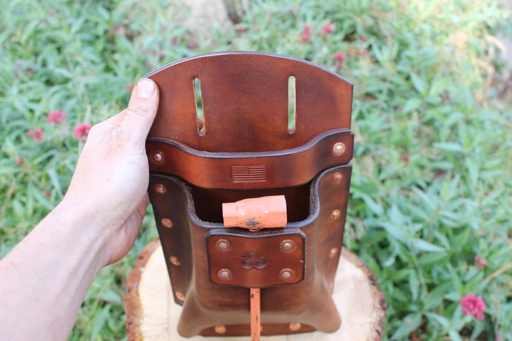 The wedge pouch held at an angle, catching the light across its burnished edges